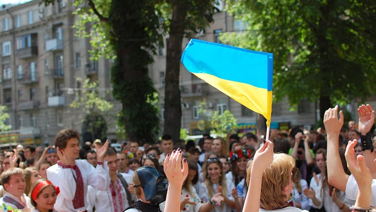 Люди у вишиванках підносять прапор України на літній вулиці