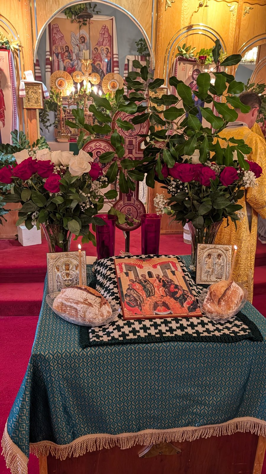 Close view of the tetrapod with prosphora, the Pentecost icon, and roses