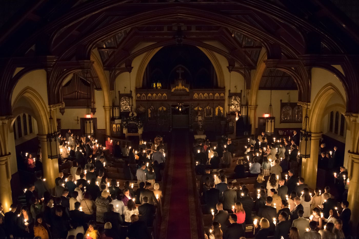 The faithful holding lit candles in the darkness at the Orthodox Pascha midnight service.