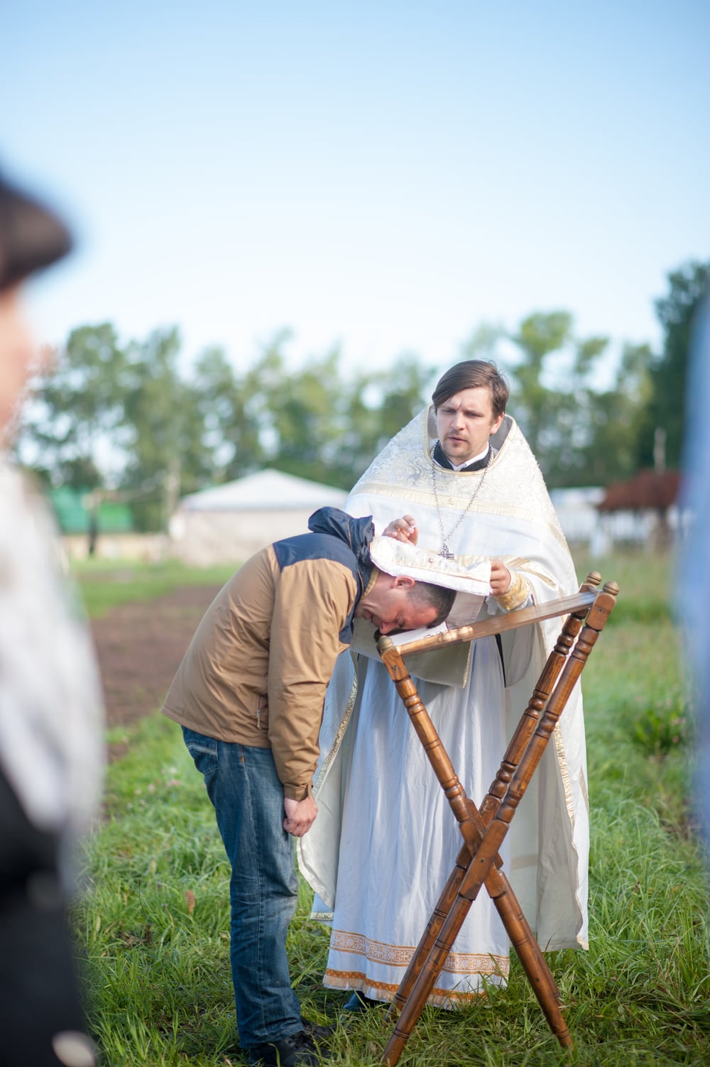 An Orthodox priest hearing a person's confession, his stole laid over their bowed head at the analogion.