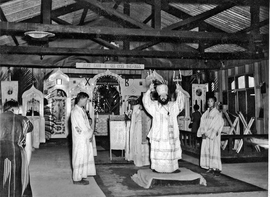 Archbishop John celebrating the Divine Liturgy in the tent cathedral on Tubabao Island, lifting the episcopal candles as acolytes stand by